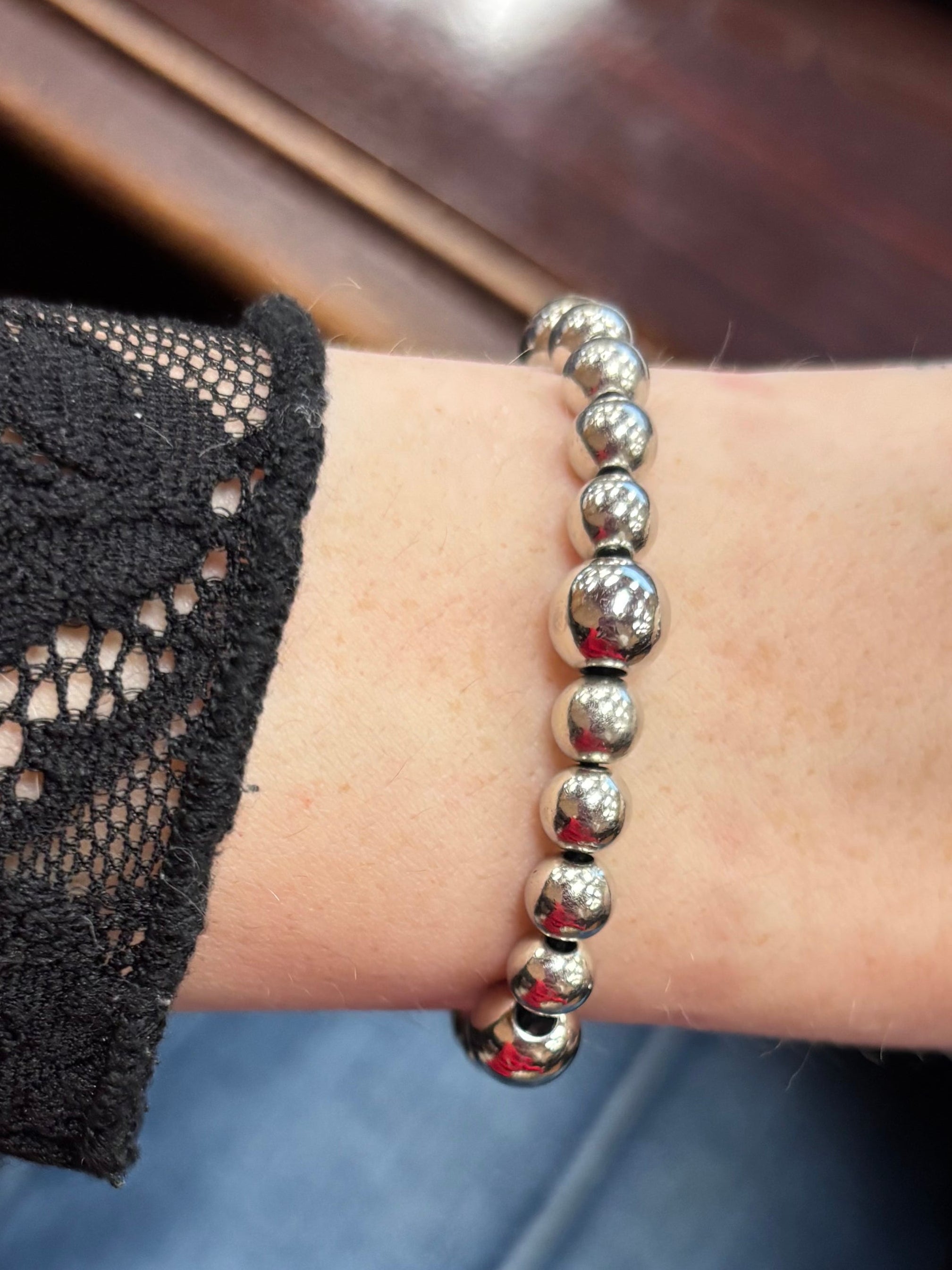 Person wearing studded bracelets on a desk with a typewriter in the background