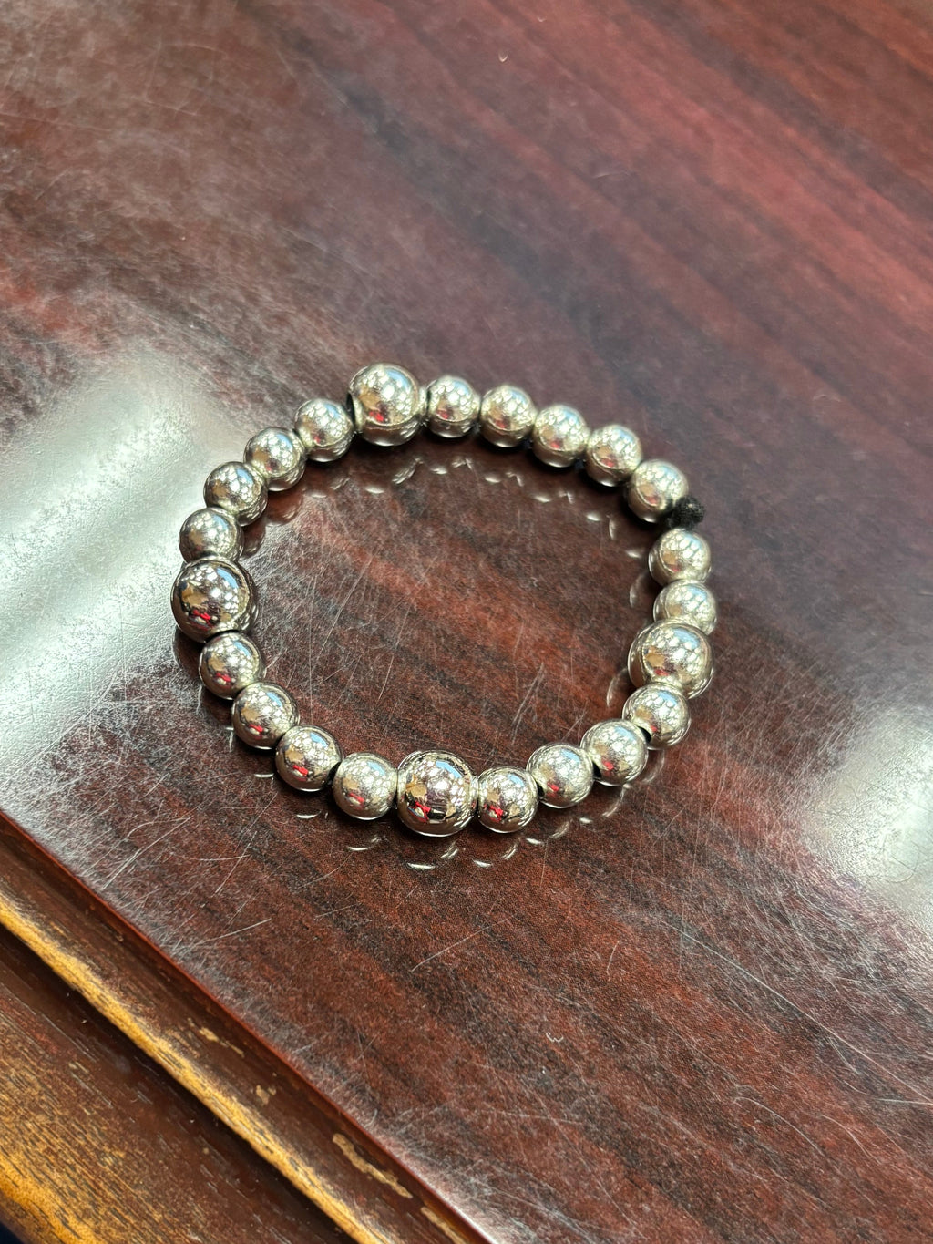 Silver beaded bracelet on a wooden surface